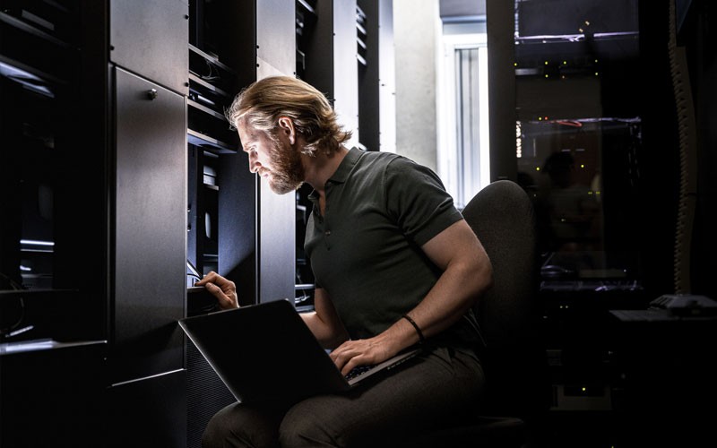 Ensure your infrastructure is designed to power all your applications IT engineer on laptop computer in server room