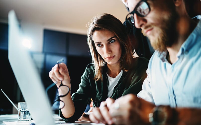 Businessman and businesswoman collaborating together on a laptop