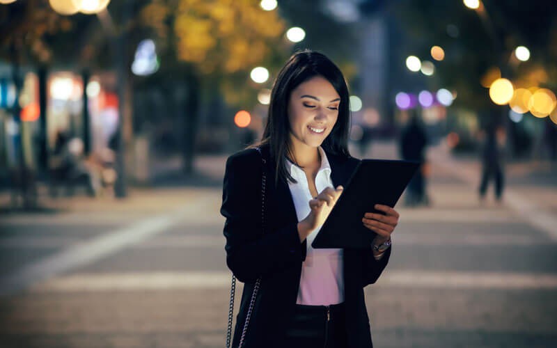 Business woman in street at night using tablet