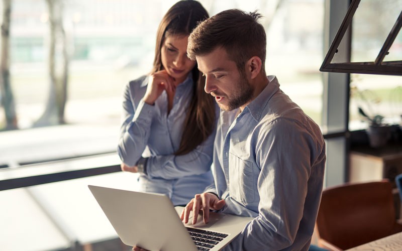 Coworkers collaborating over laptop device