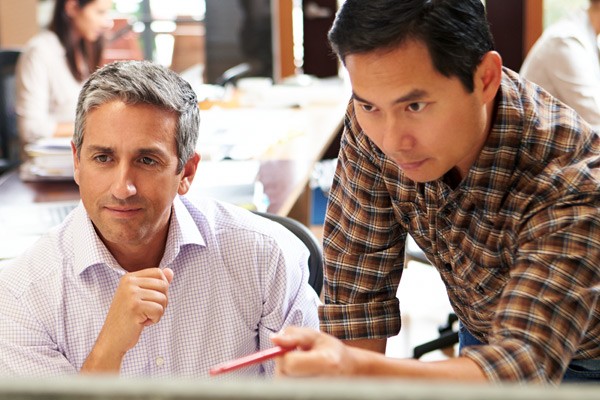 Businessman with pen points at something on computer