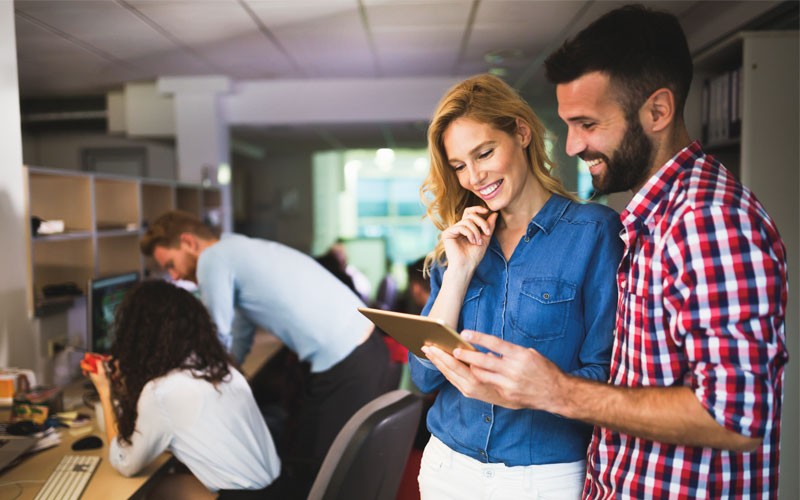 Two employees collaborating over tablet device