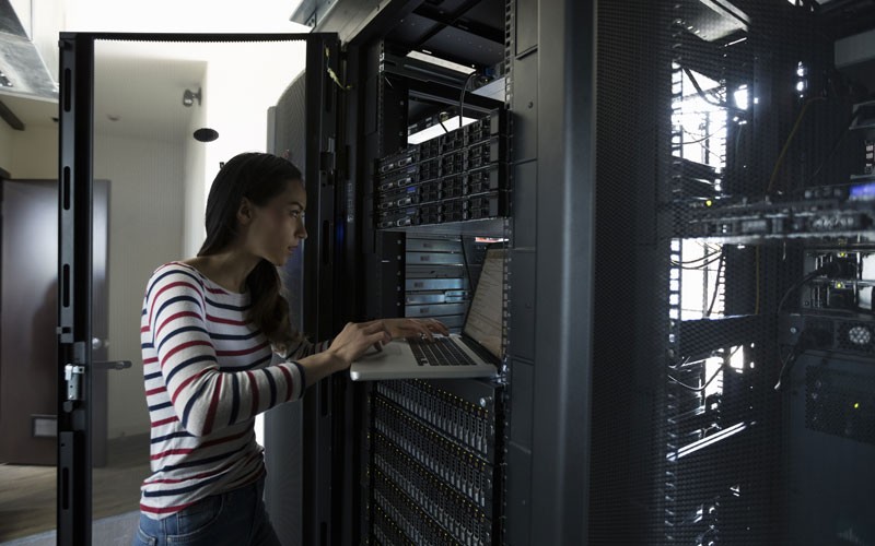 woman-examining-laptop-screen-in-server