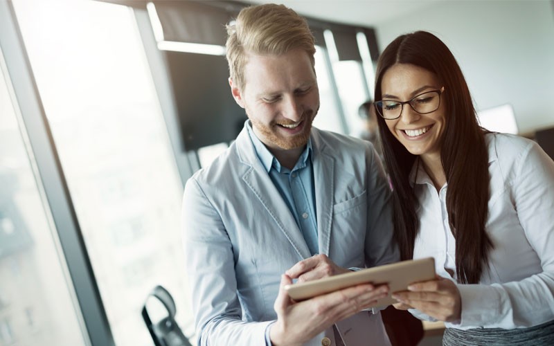 Two professionals smiling over tablet device