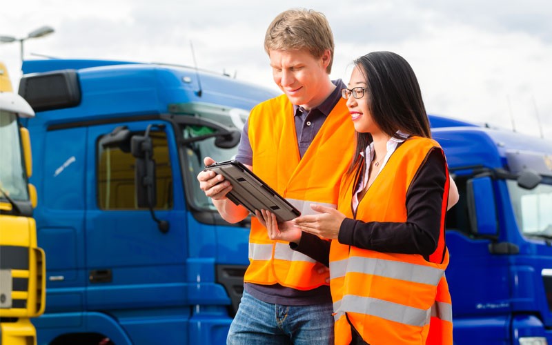 Two people next to truck looking at tablet