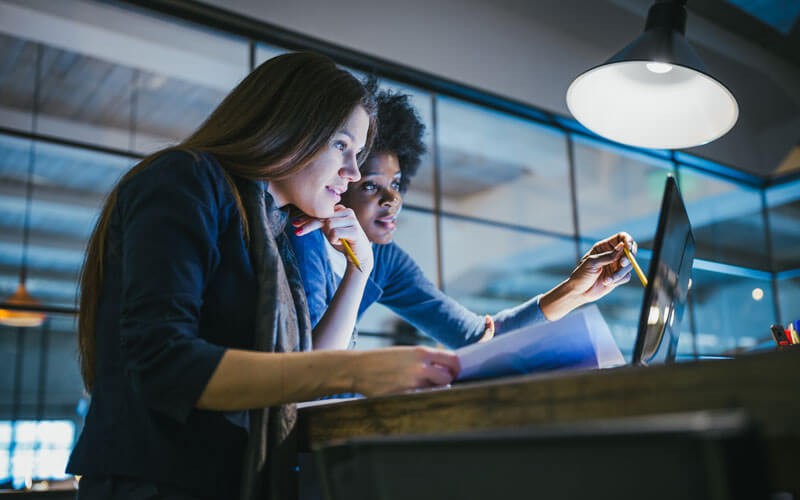 Linux containers help you get applications to market fast Two colleagues work on laptop computer in office at night