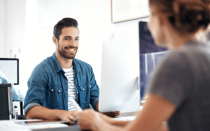 Two smiling colleagues on desktop computers