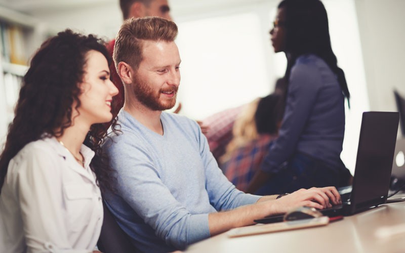 Two employees collaborating at laptop