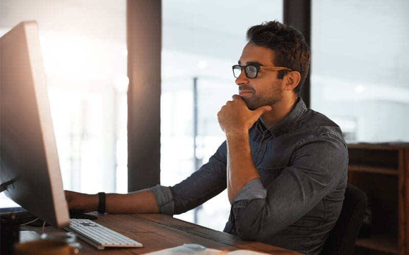 Man smiling at desk working on device