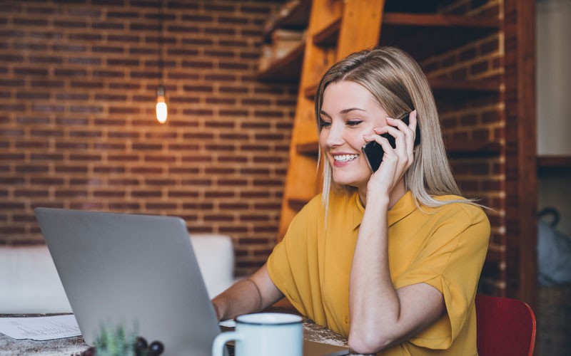 Woman working on mobile phone and laptop remotely