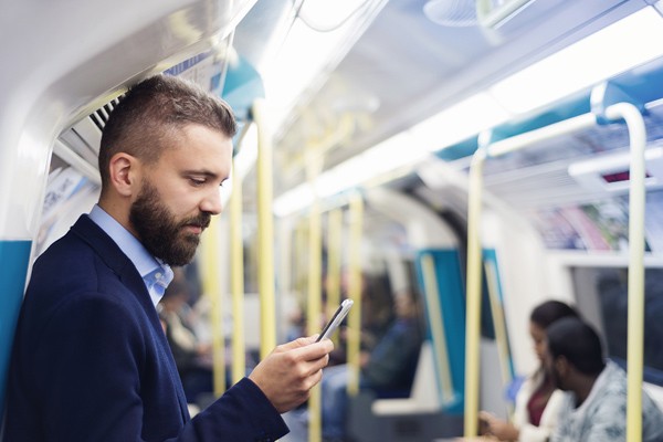 Businessman reading article on iPhone while on the subway 