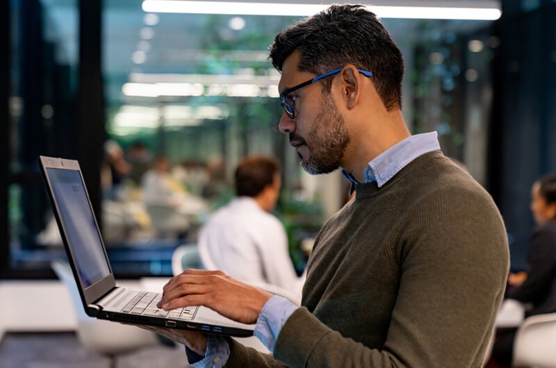 Businessman on laptop device standing in office