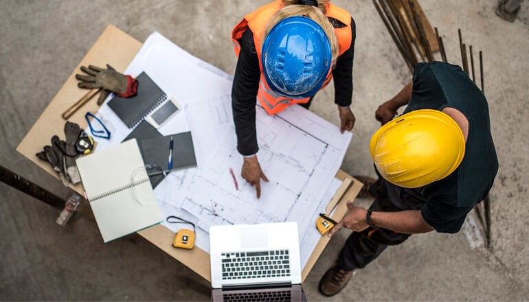 Construction workers in hard hats on site reviewing plans