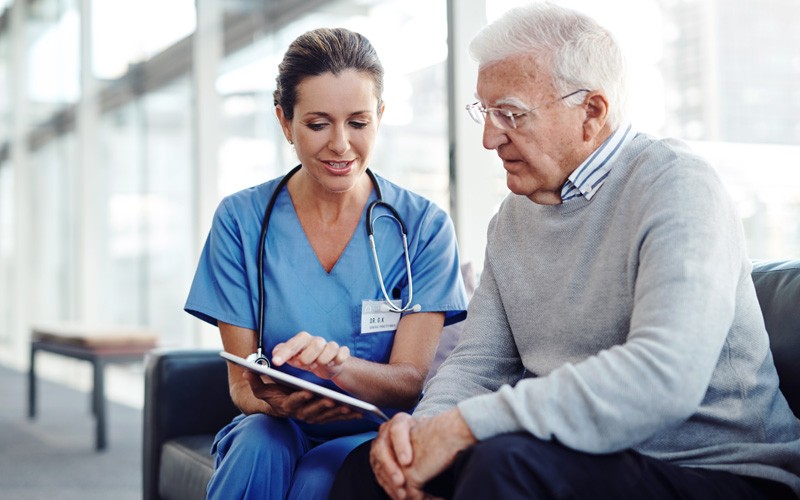 Nurse with tablet explains treatment options to elderly patient 