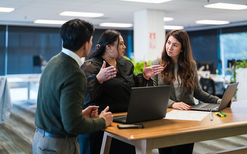Teammates collaborate at an office table using a Radius workshop, reviewing content and sharing ideas during a session.