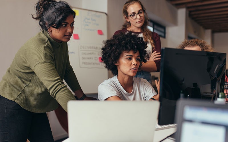 Team collaborating in the office around desktop computer